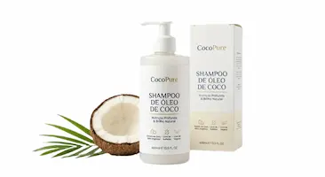 Shampoo de óleo de coco CocoPure, com 400ml, em garrafa de bomba e caixa de embalagem. O rótulo destaca hidratação profunda e brilho natural, com metade de coco fresco e folhas verdes ao lado. Livre de sulfato e vegano, sobre fundo branco puro.